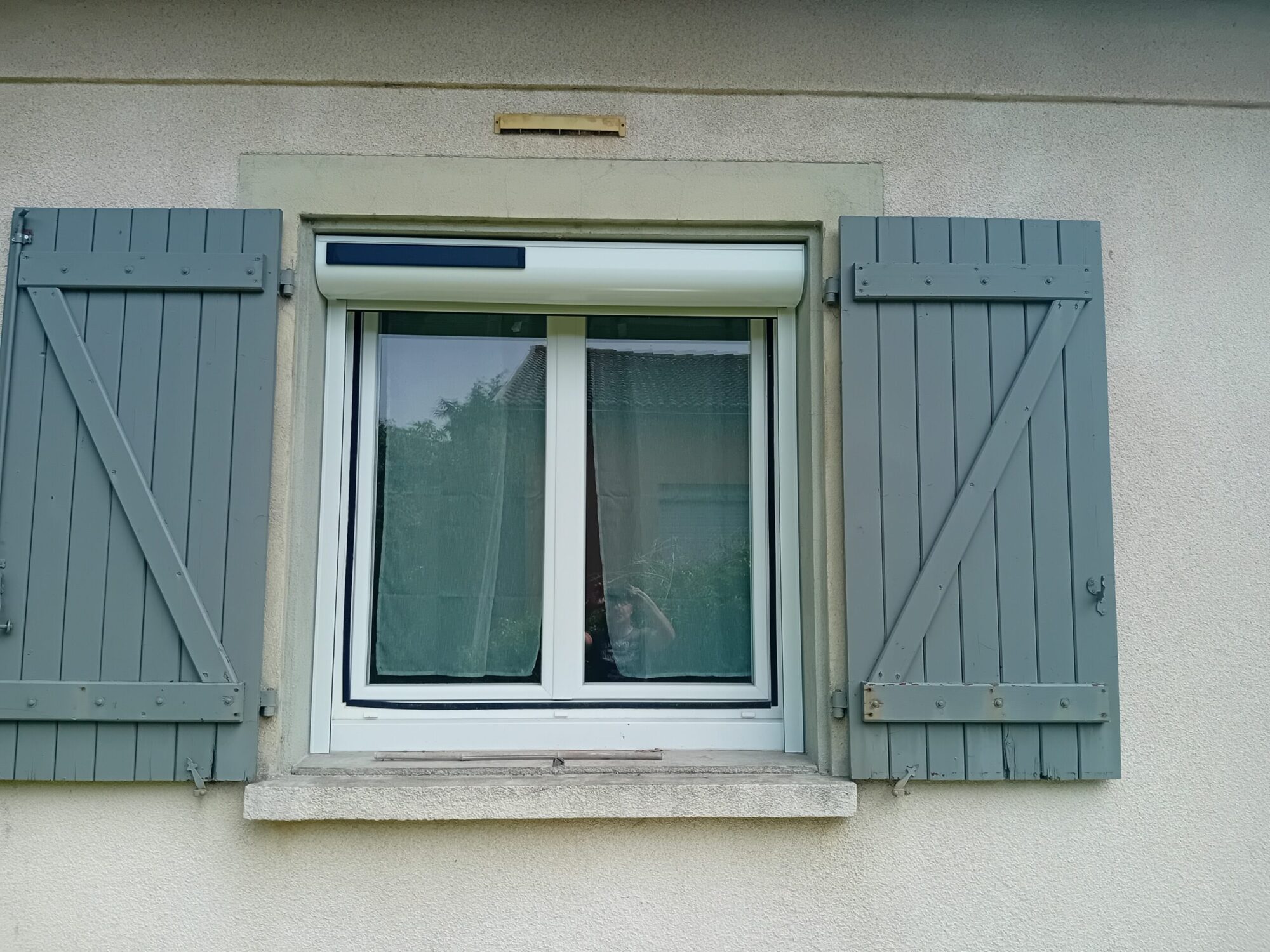 Fenêtre avec volets en bois gris, élément de menuiserie moderne.