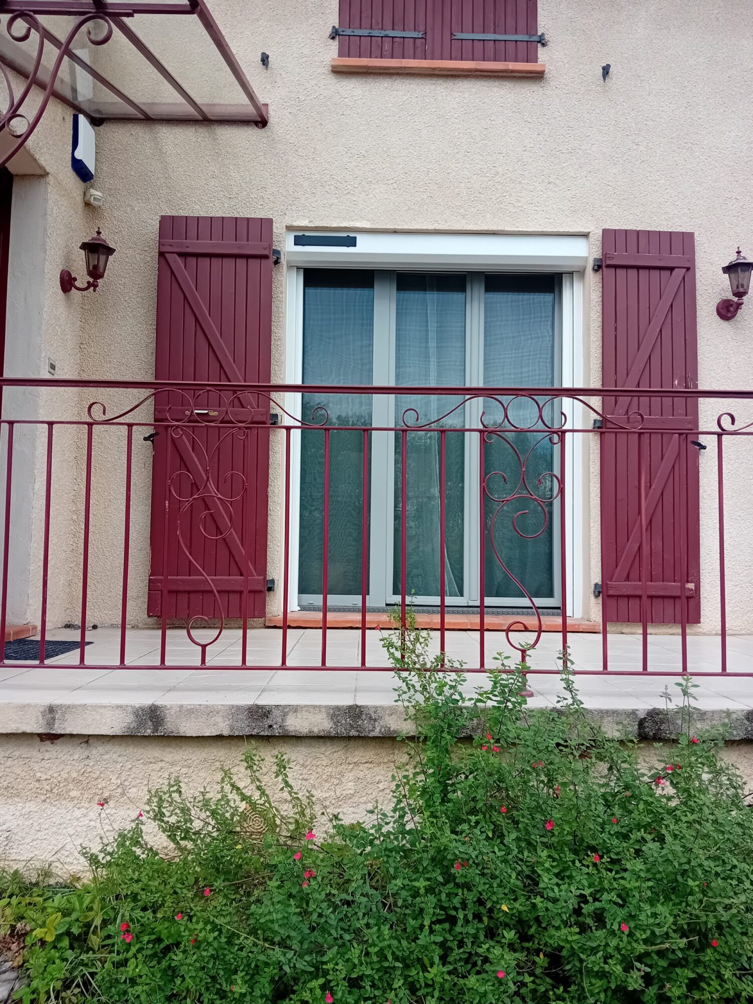 Fenêtre avec volets battants en menuiserie et balustrade en fer.