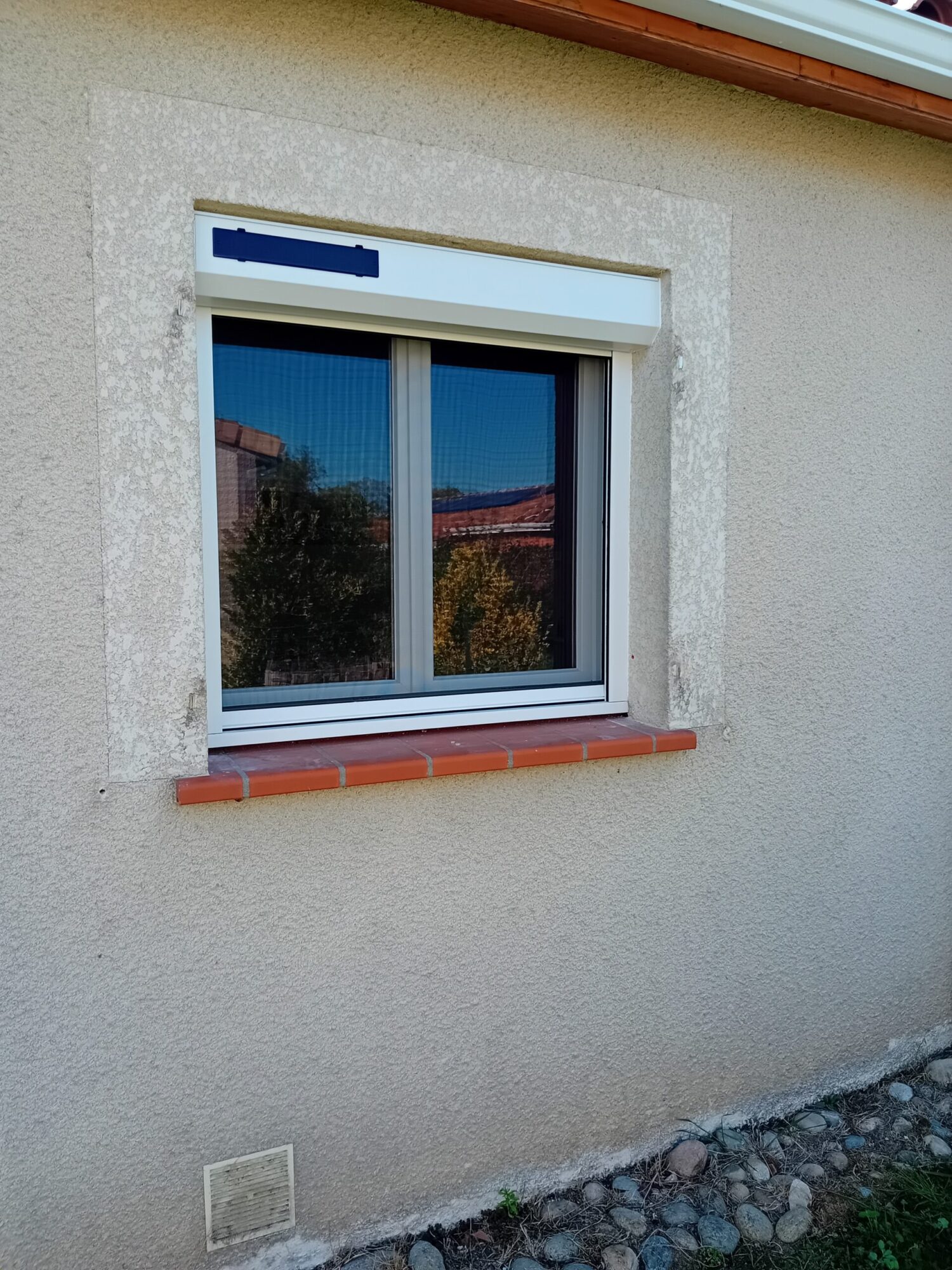 Fenêtre en menuiserie avec cadre en PVC et rebord en carrelage.