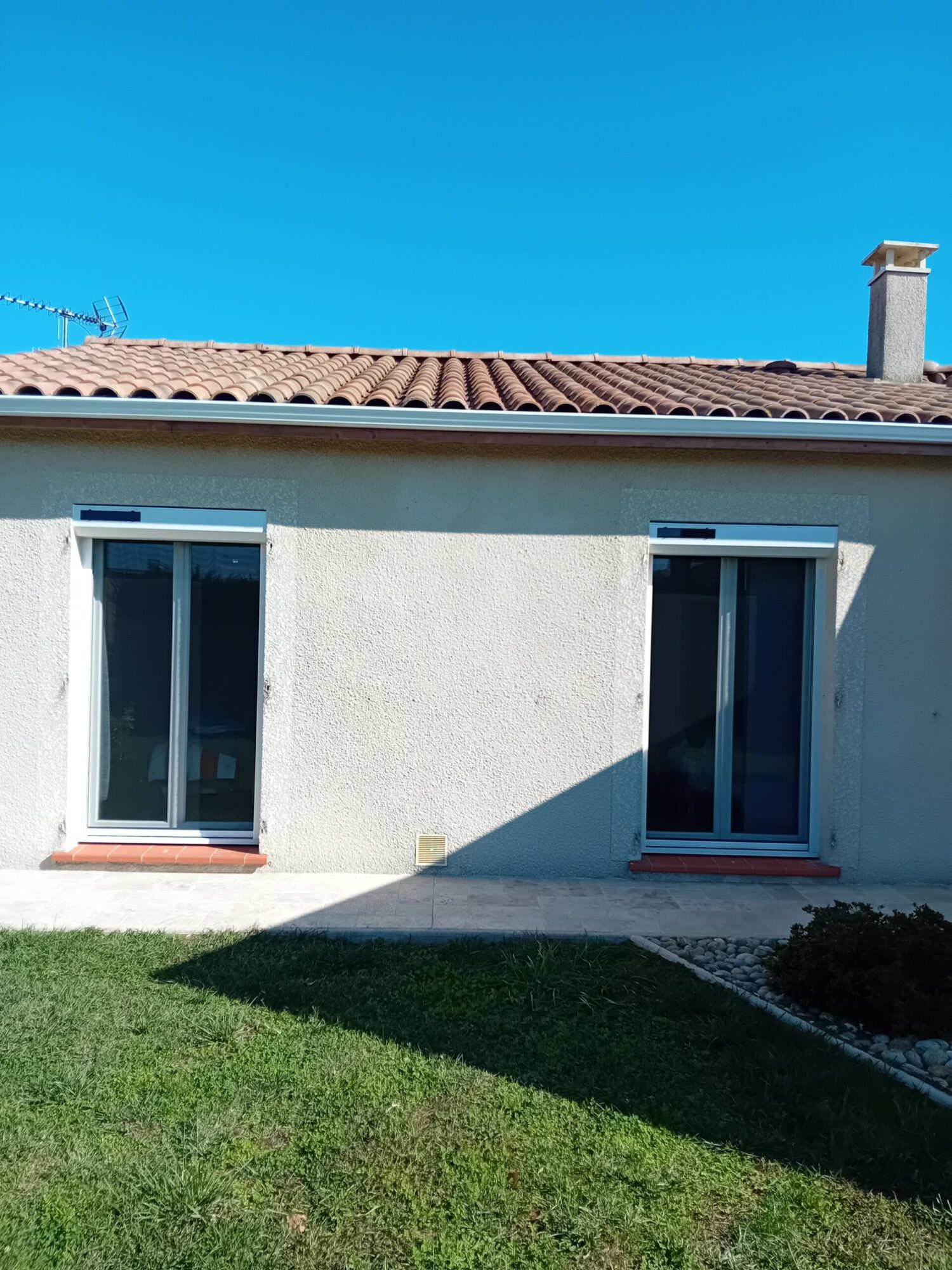 Façade d'une maison avec menuiserie et fenêtres en verre.